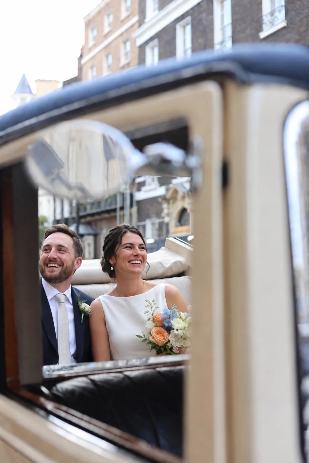 A bride and groom seated inside the 1930s Rolls-Royce 20/25 Landaulette, seen through the open window, the bride holding a bouquet